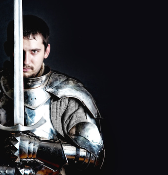 Foto von Mann in Ritterrüstung mit Schwert senkrecht nach oben haltend