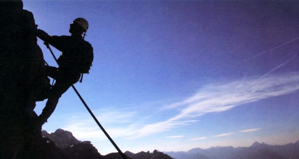 Foto vom Bergsteiger am Fels im Gegenlicht